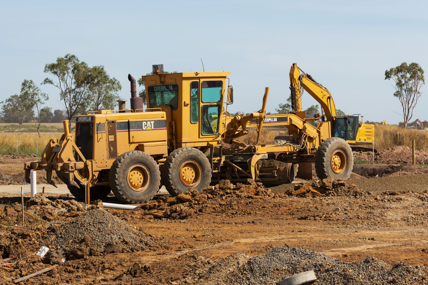 Motor grader and excavator working on a construction site.