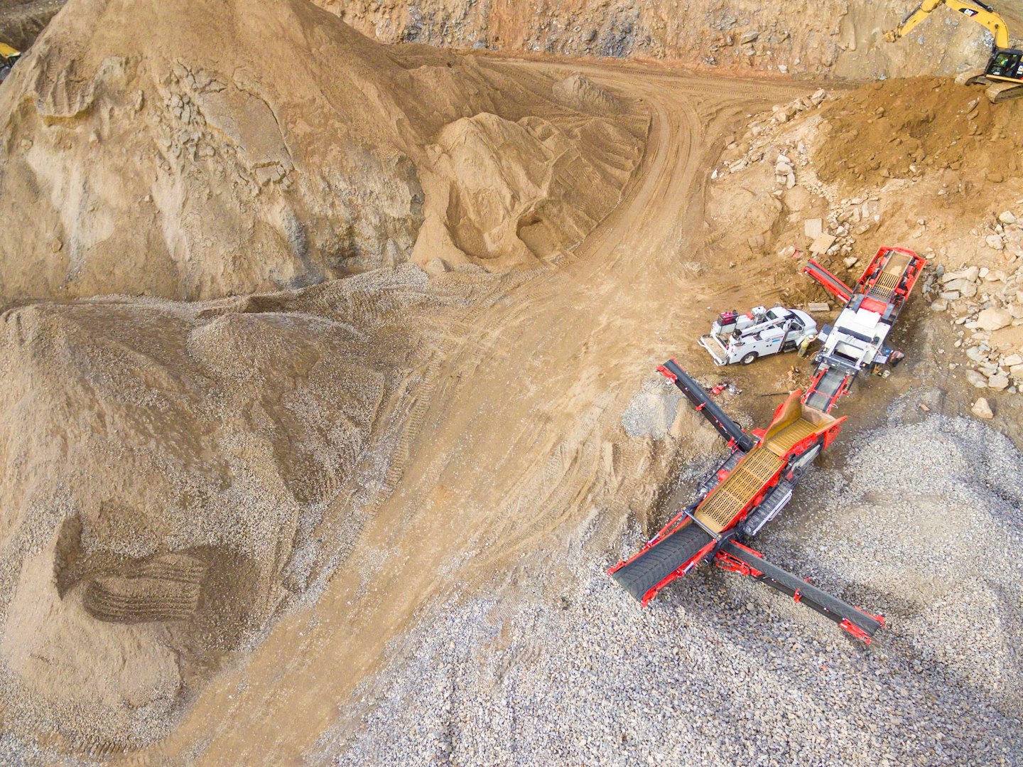Industrial quarry machinery processes sand and gravel under bright daylight.