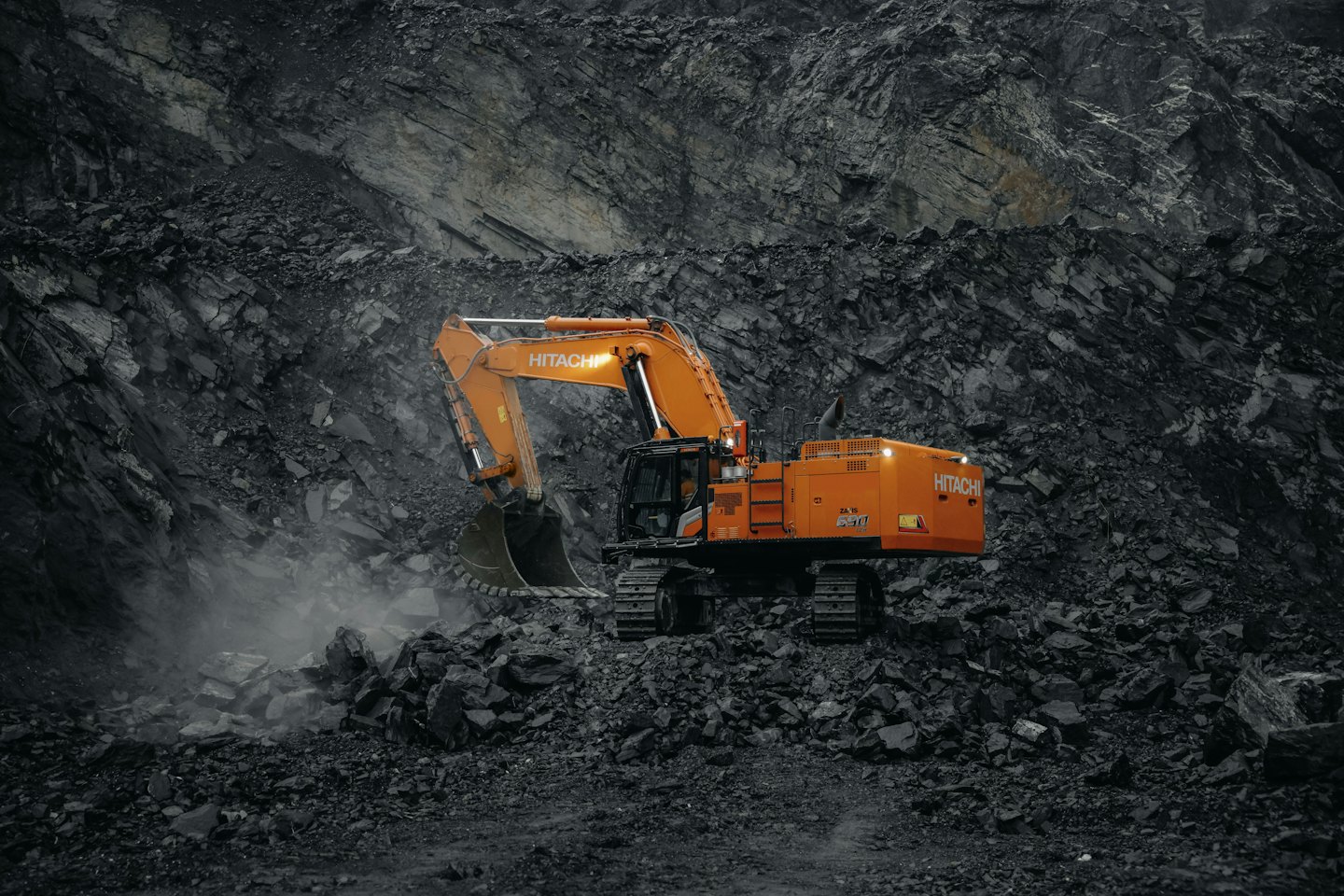 Orange excavator digging in a rocky quarry.