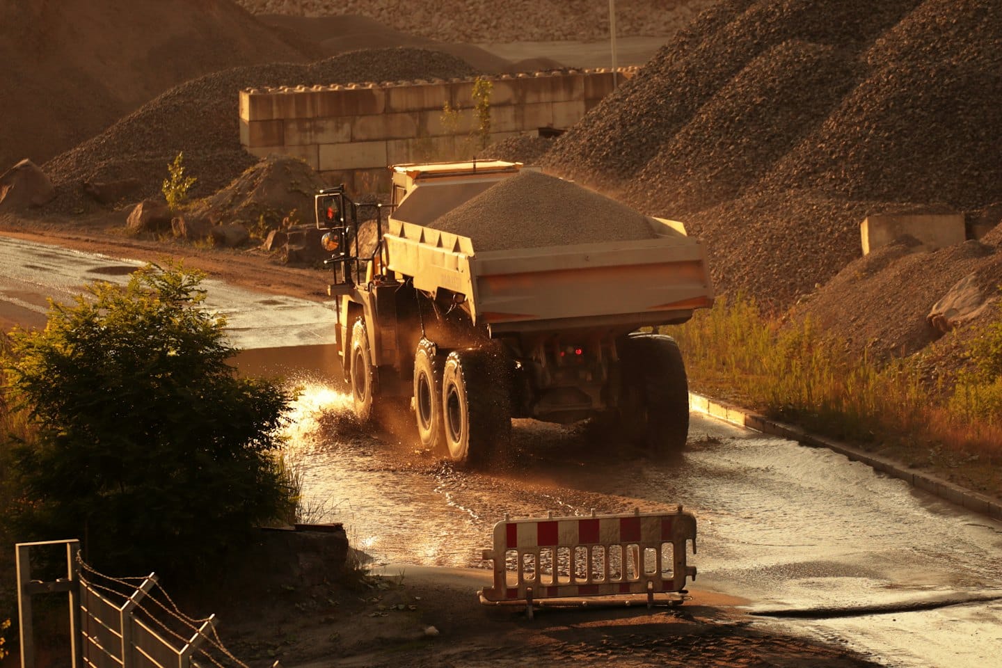 An articulated dump truck drives through a wet construction site.