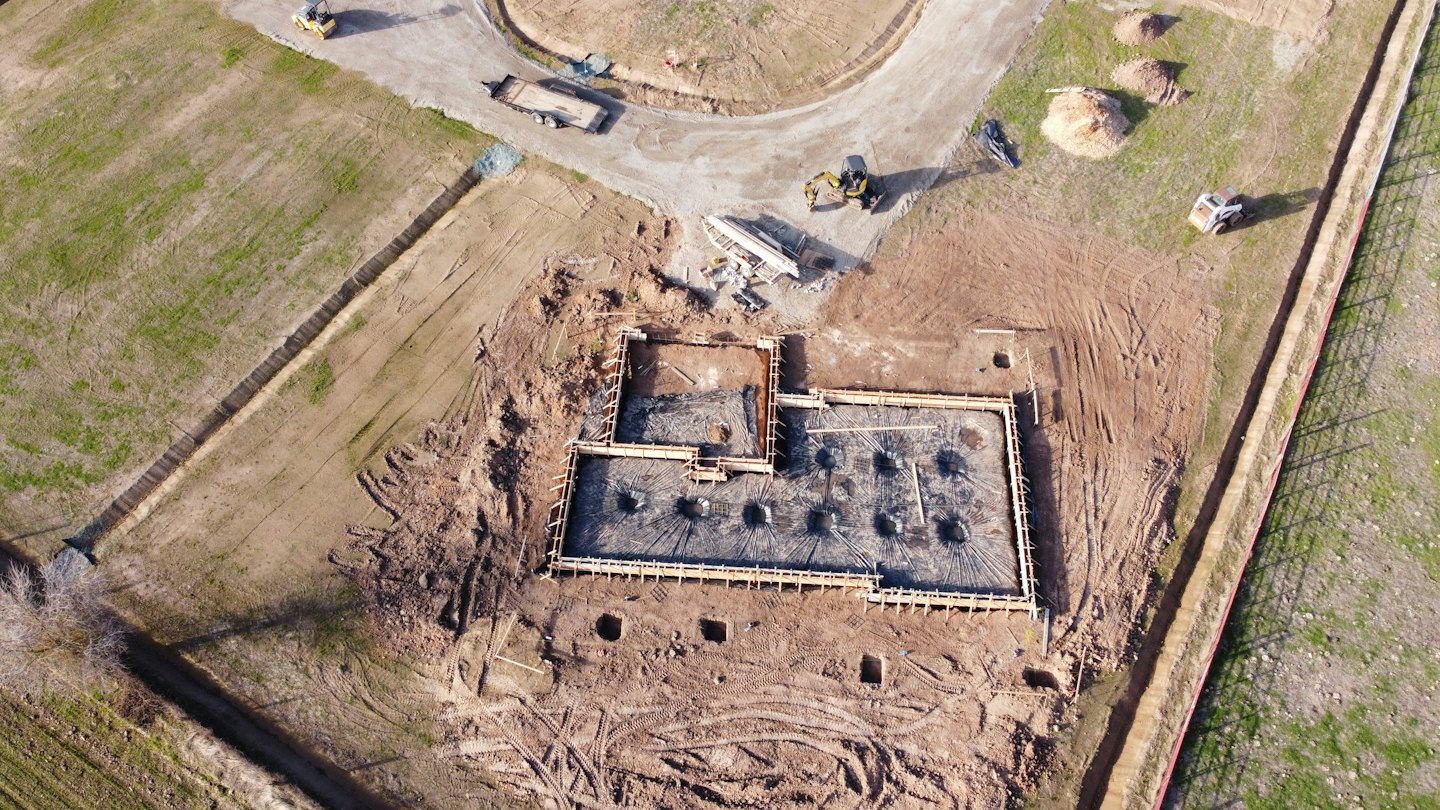 Aerial view of a building foundation under construction with formwork and rebar.