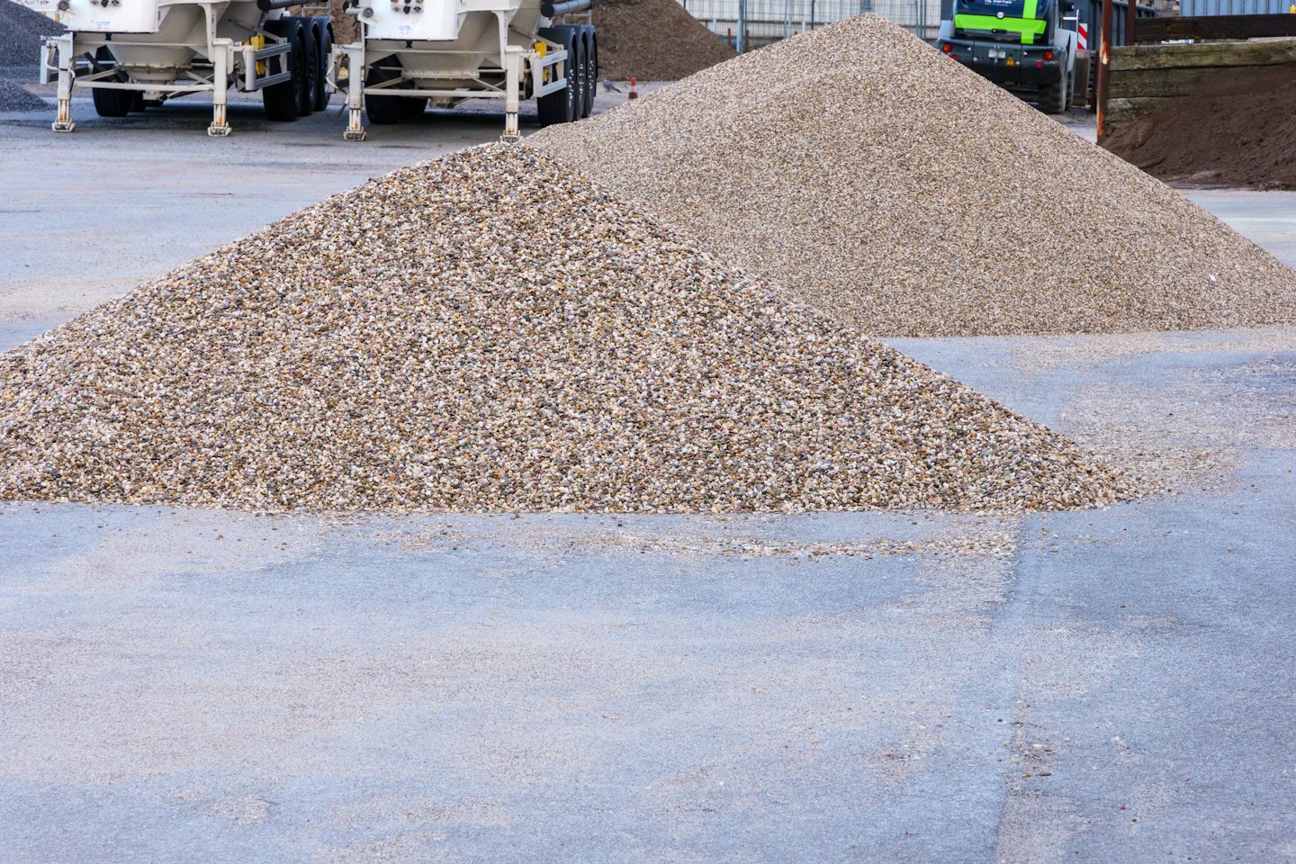 Two large piles of gravel sit on a concrete surface.